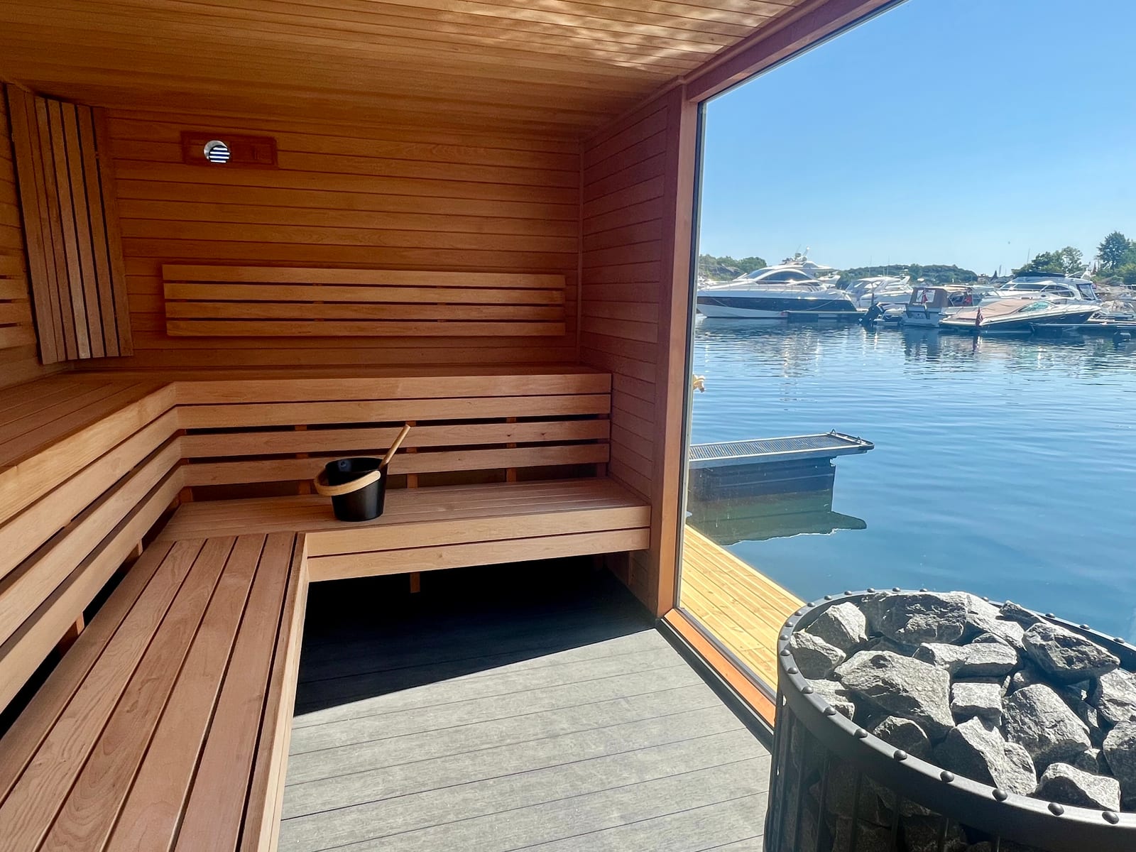 Badstuens L-formede benk med utsikt mot havna gjennom panoramavinduet